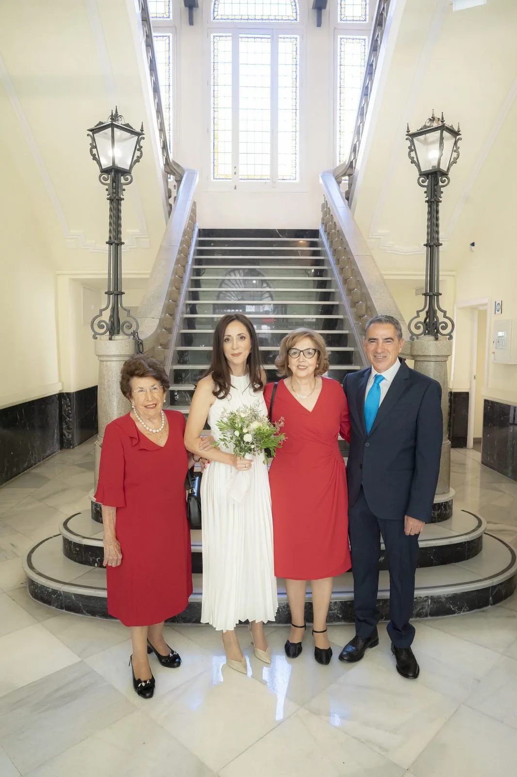 La novia posa con tres familiares al pie de una escalera de mármol con farolas