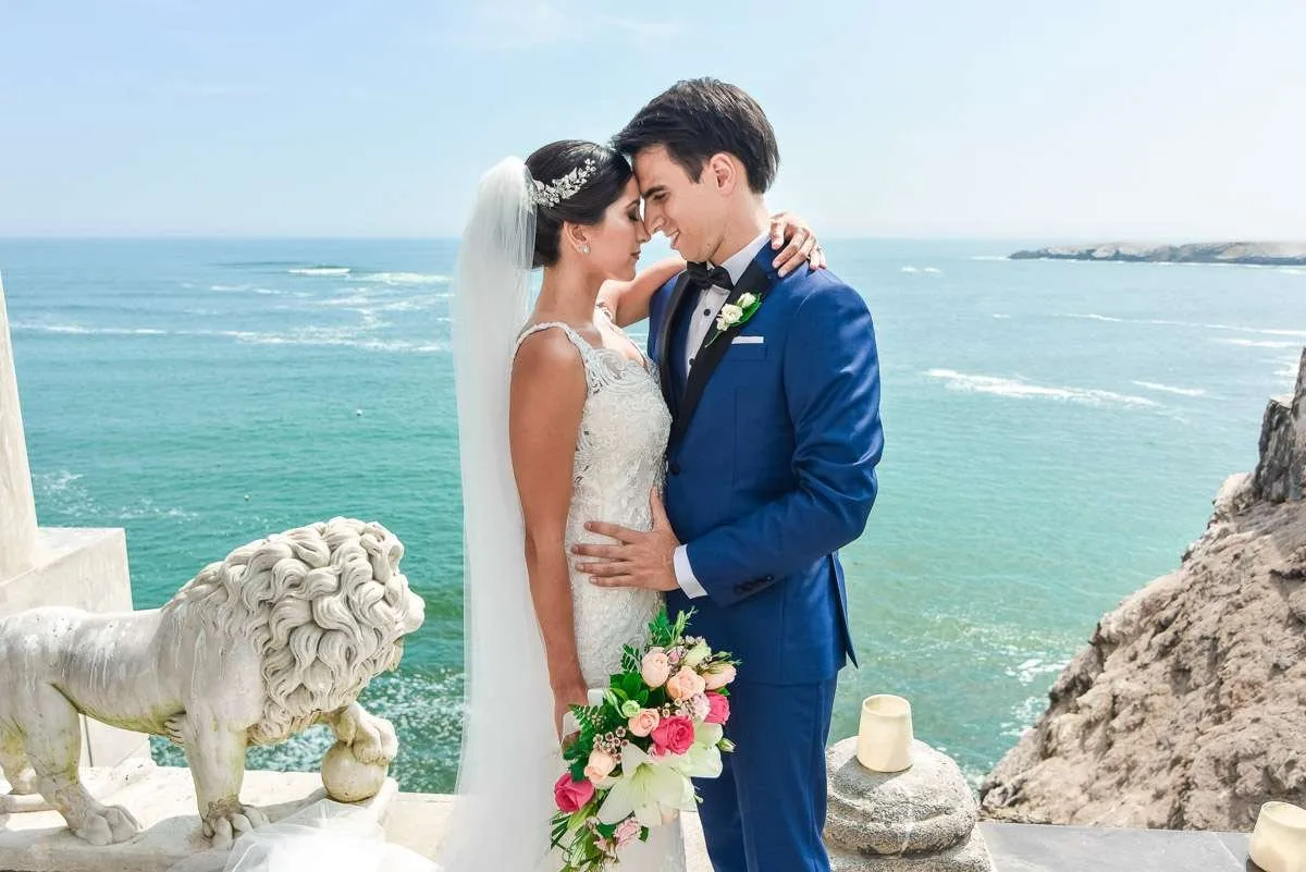 Couple embracing by the sea beside a stone sculpture