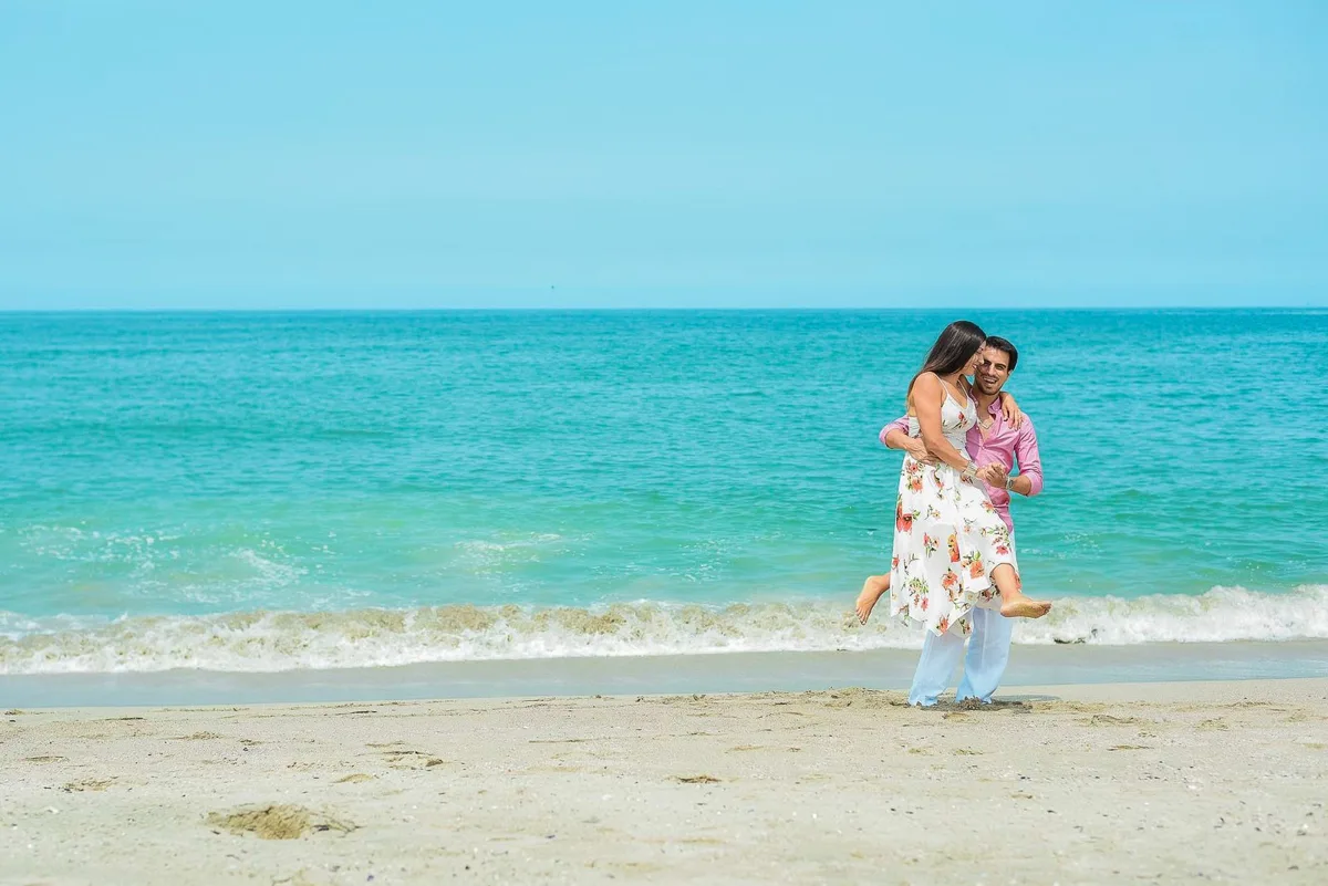 Woman in a floral dress walking along a beach shoreline