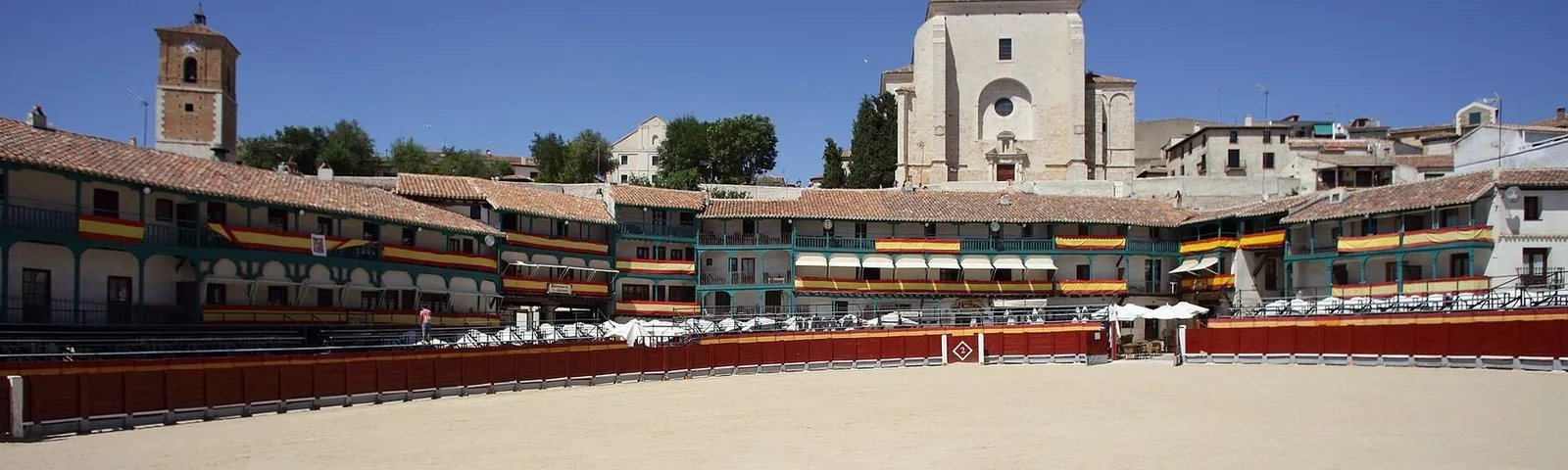 Arcaded square with green balconies and a church behind