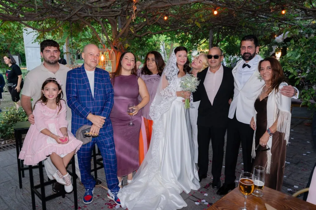 Novios y familiares posan bajo una pérgola con luces