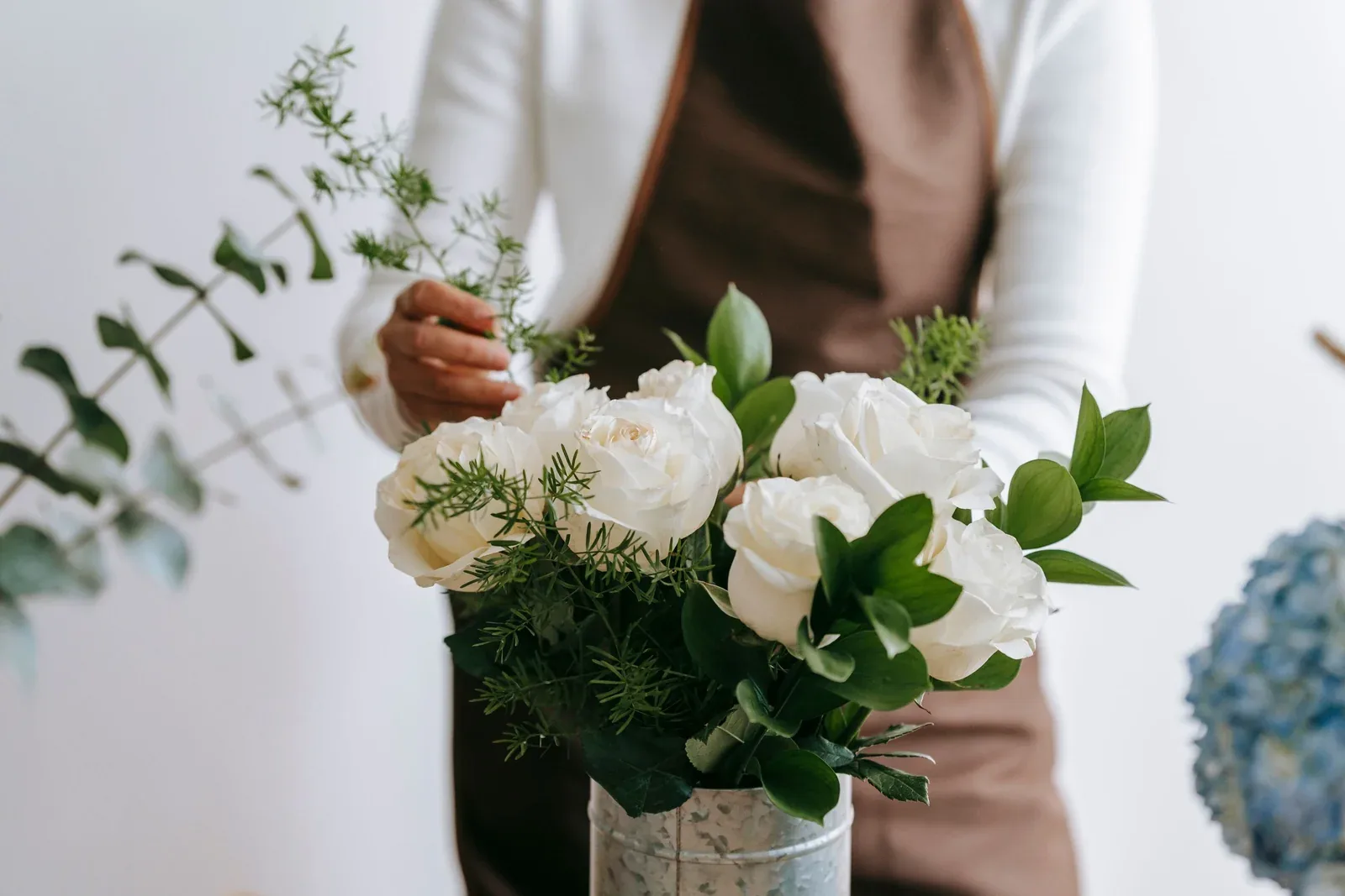 A florist prepares a bouquet of white roses and eucalyptus