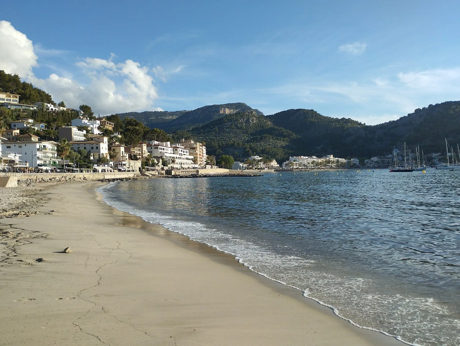 Playa de arena con un pueblo y montañas al fondo