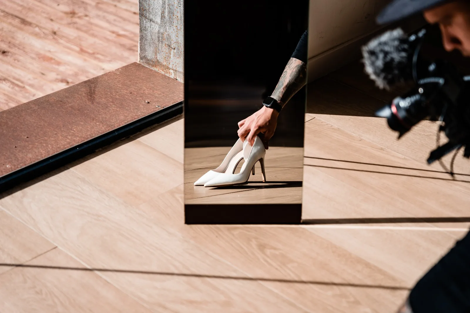 Reflection in a mirror: a bride’s white shoes and the photographer’s camera