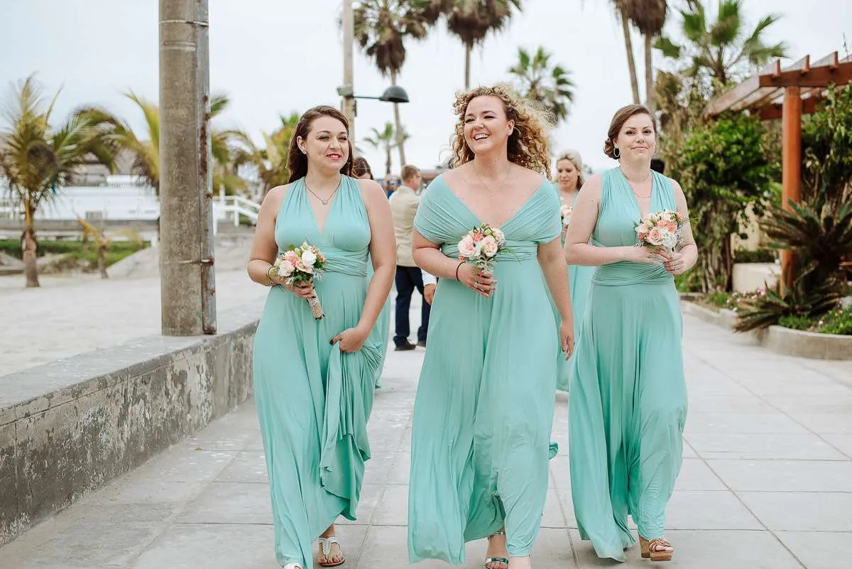 Bridesmaids in sea-green dresses walking together along a path