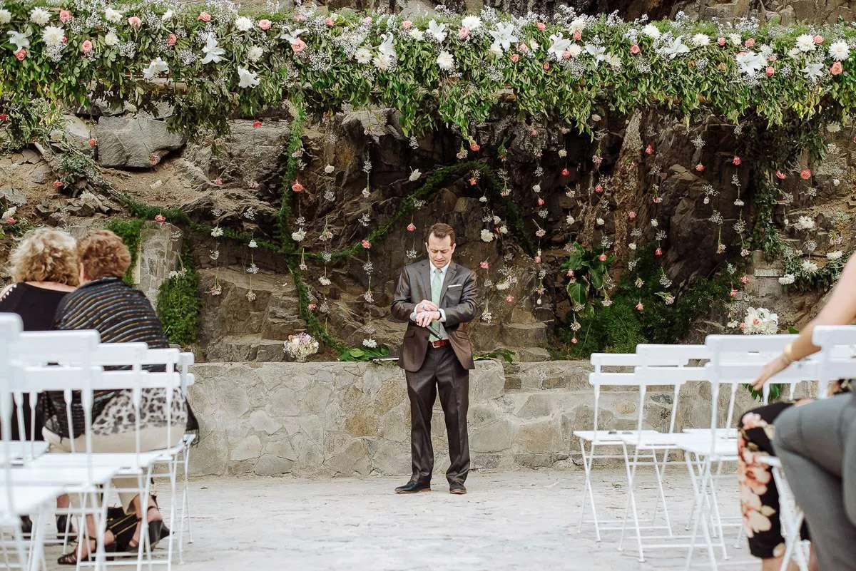 A stone garden with white chairs set out for a ceremony