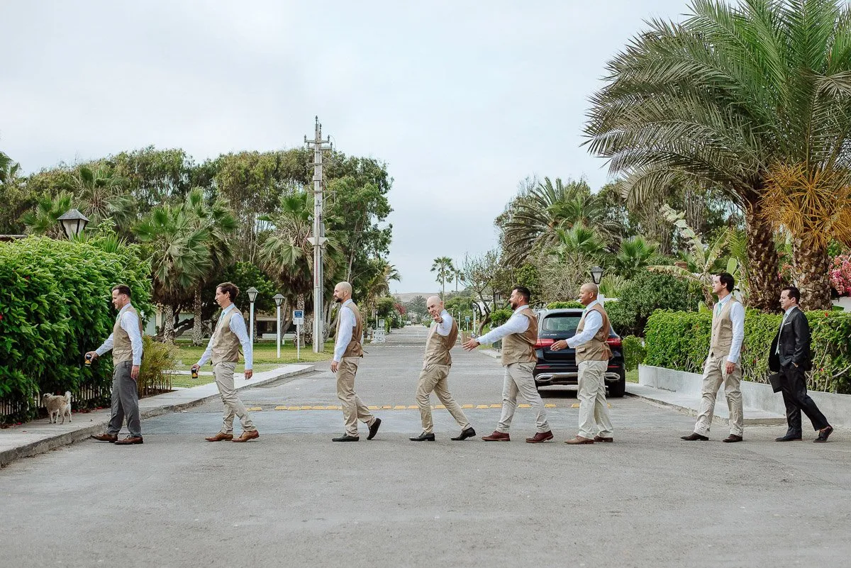 A group of men in light suits crossing a street in single file