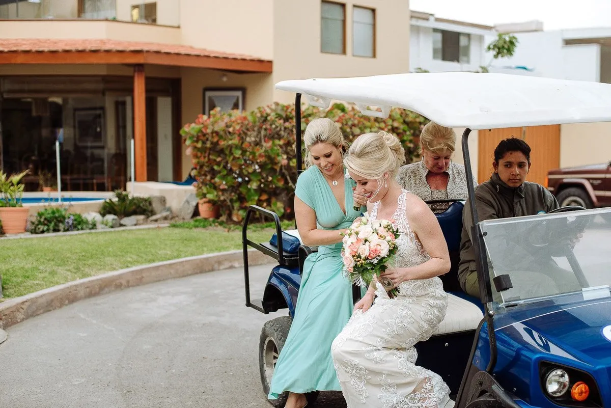 A bridesmaid helps the bride, bouquet in hand, onto a golf cart