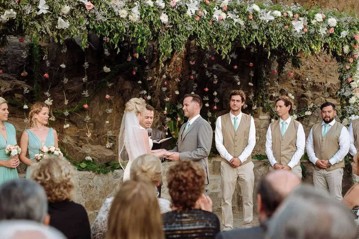 An open-air ceremony with a floral arch and guests seated