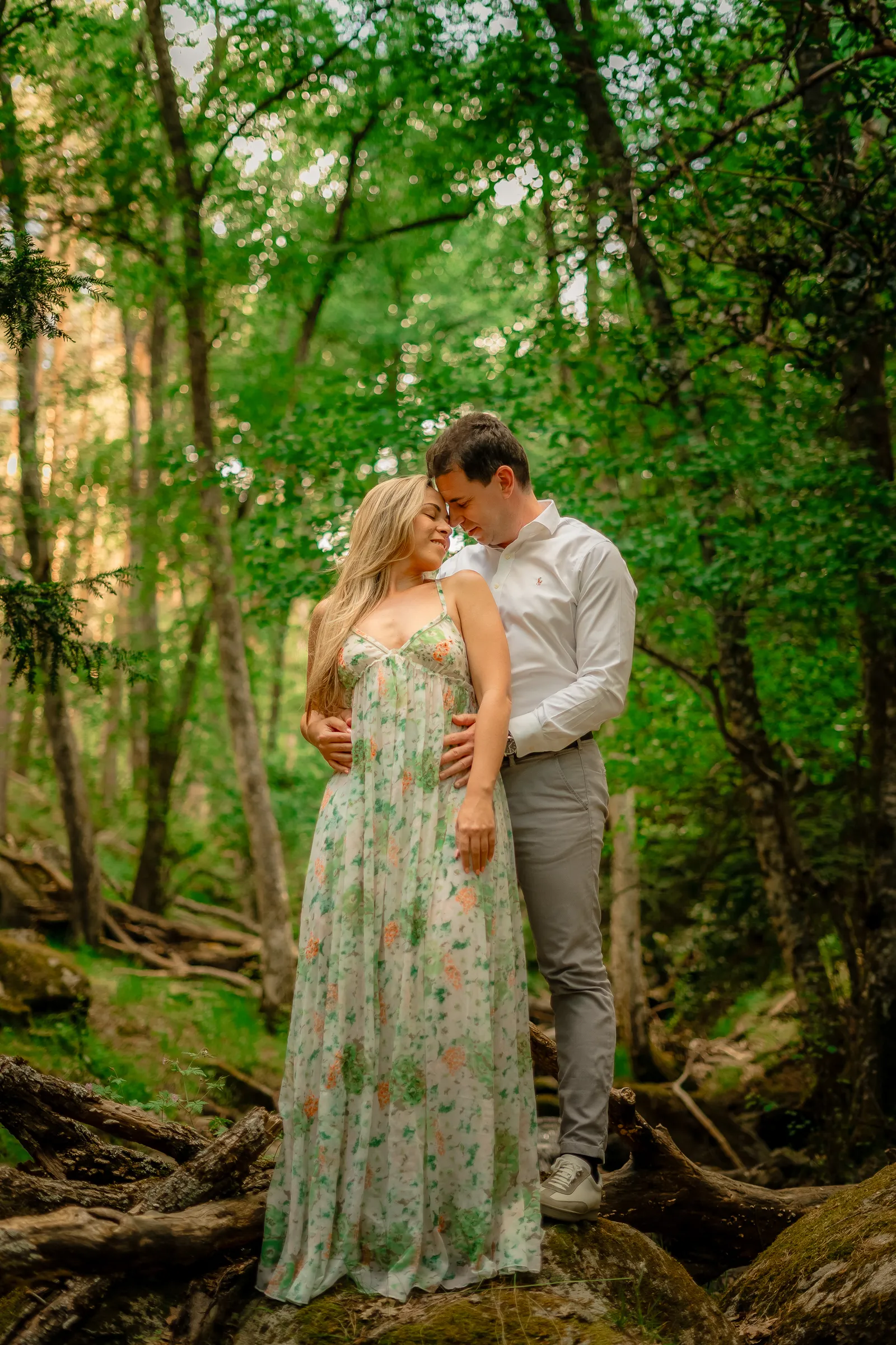 Pareja abrazada en un bosque frondoso, con vegetación verde de primavera