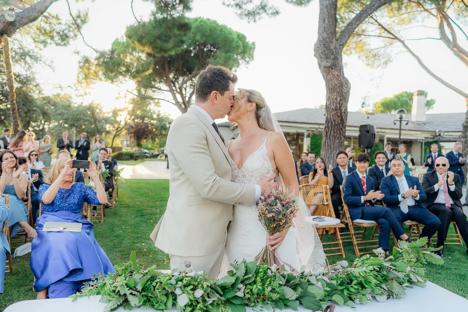 The couple kiss on the lawn as the ceremony ends