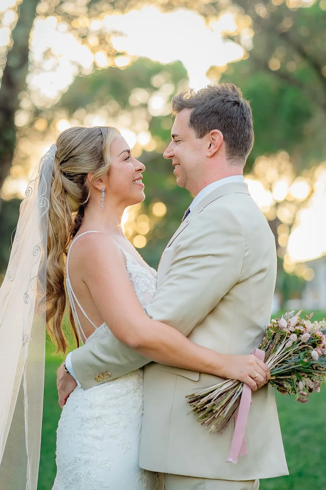 Couple embracing, she wearing a veil, in golden light