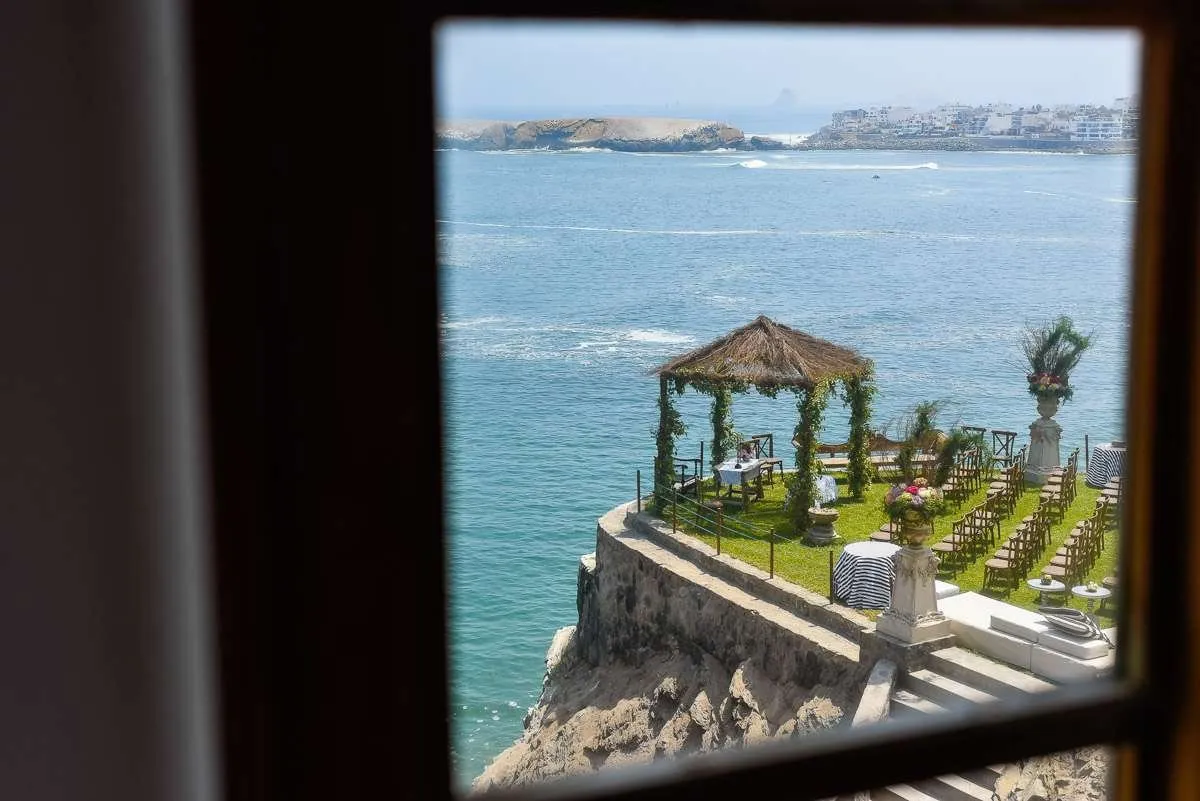 A view of the sea and a pergola seen through a window on a wedding morning