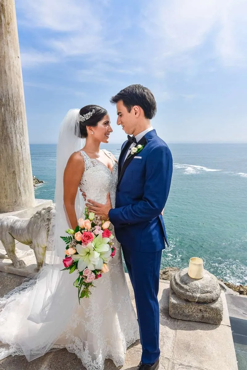 Newlyweds embracing by the sea between stone columns