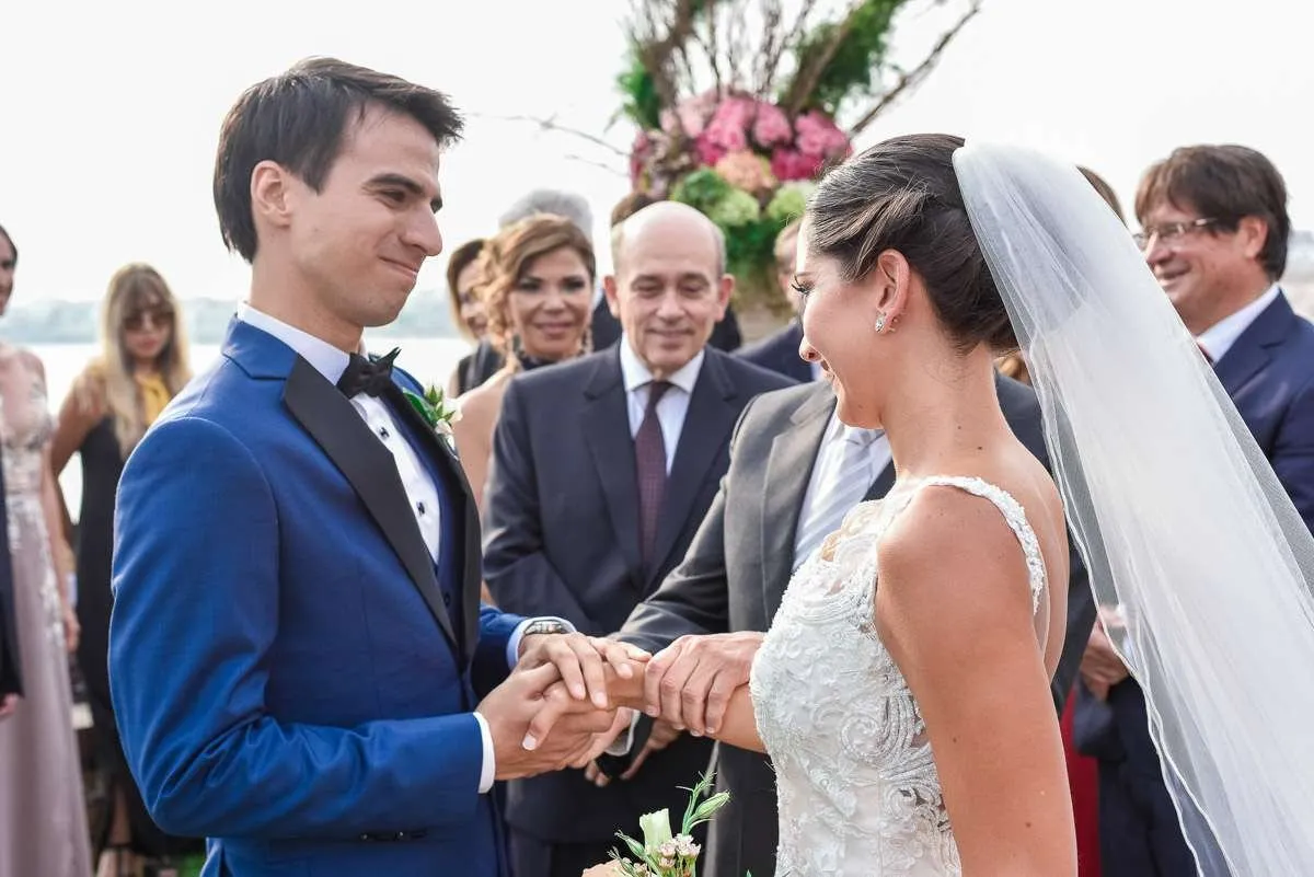 The couple exchange rings before their guests, with flowers behind