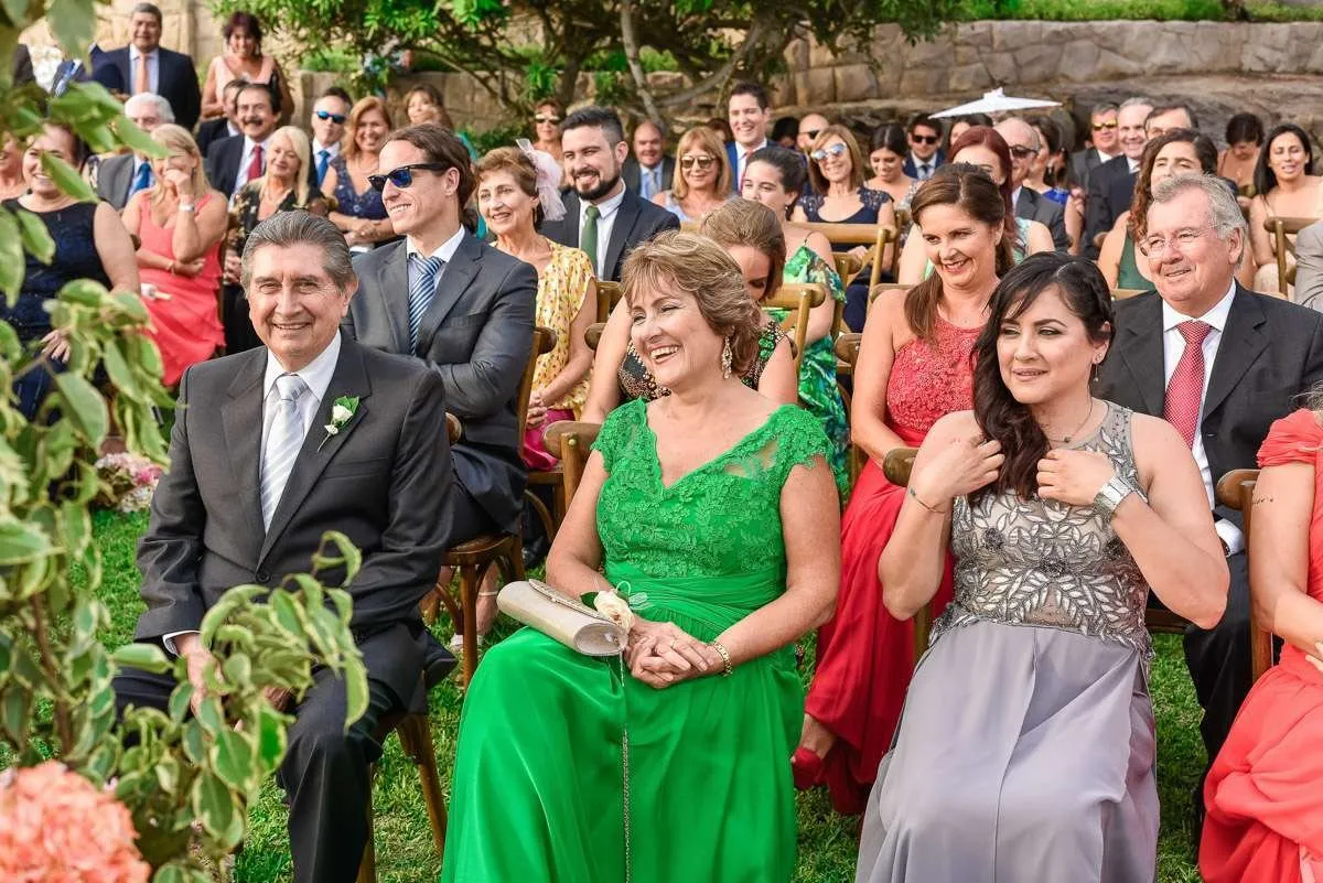 Smiling guests seated in the garden listen closely during the ceremony