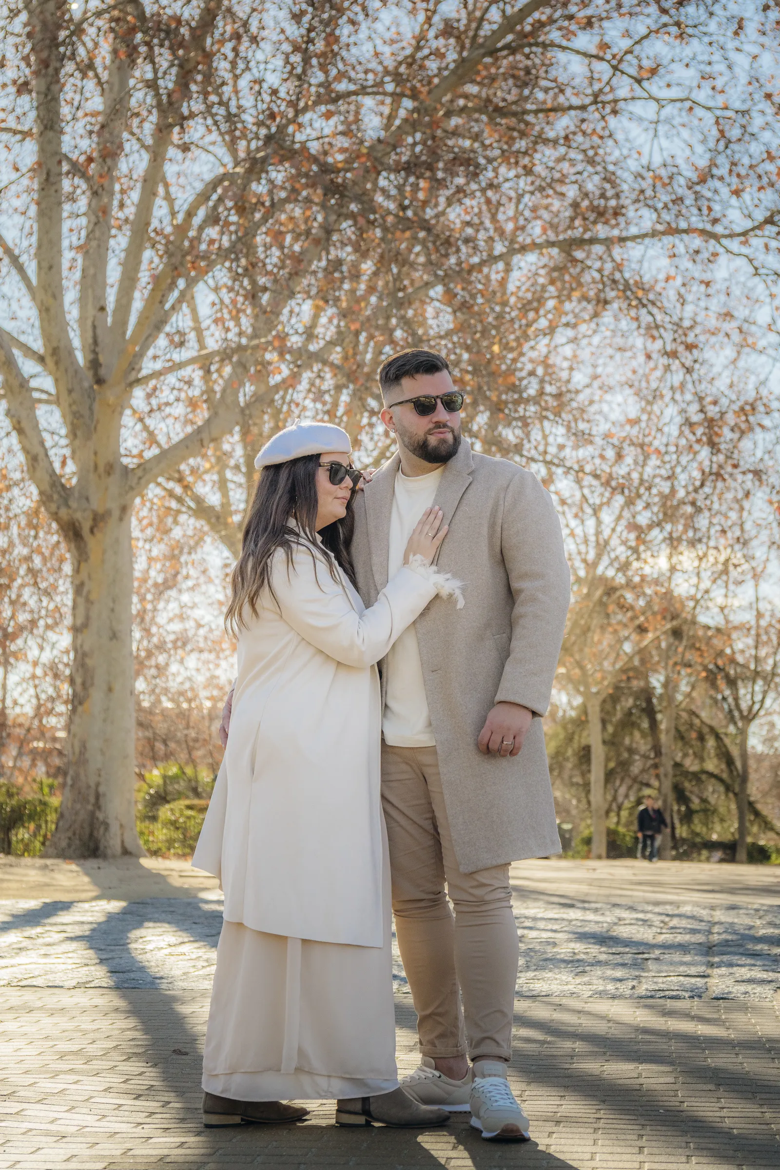 Pareja abrazada bajo un árbol sin hojas, con luz de invierno