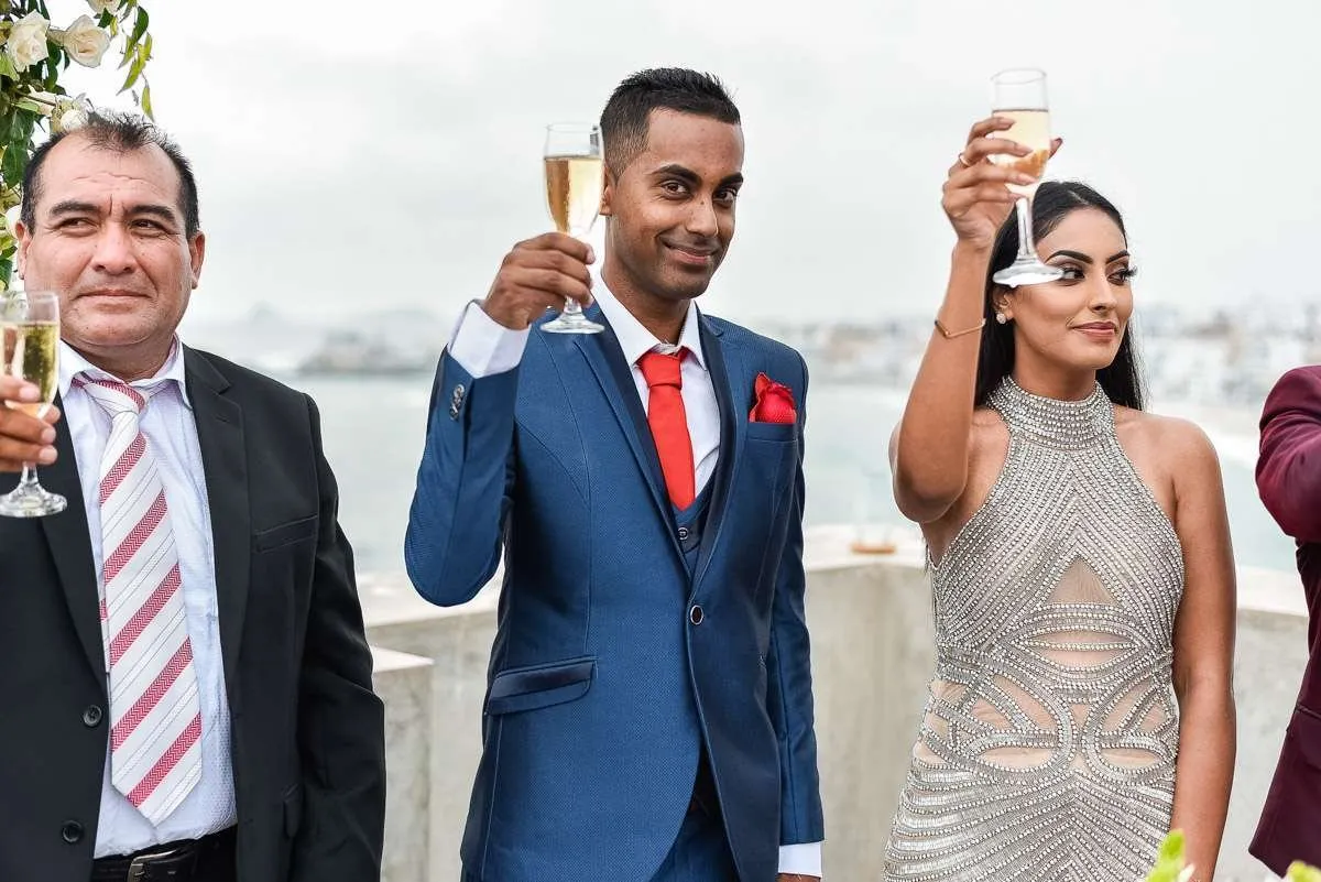 Three guests raise glasses by the sea, on a terrace