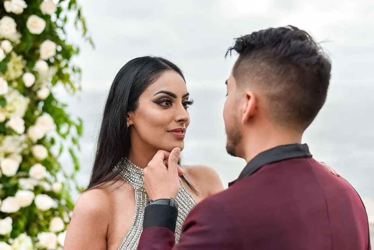 Close-up of a couple looking at each other, with white flowers behind
