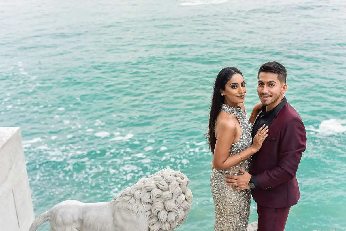 Una pareja sobre un mirador de piedra blanca frente a un mar turquesa