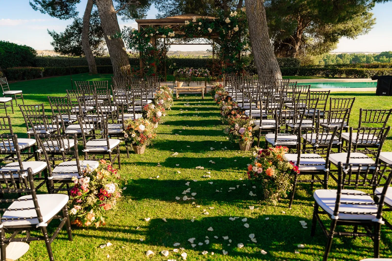 Chairs in rows on the lawn among trees, set for a ceremony