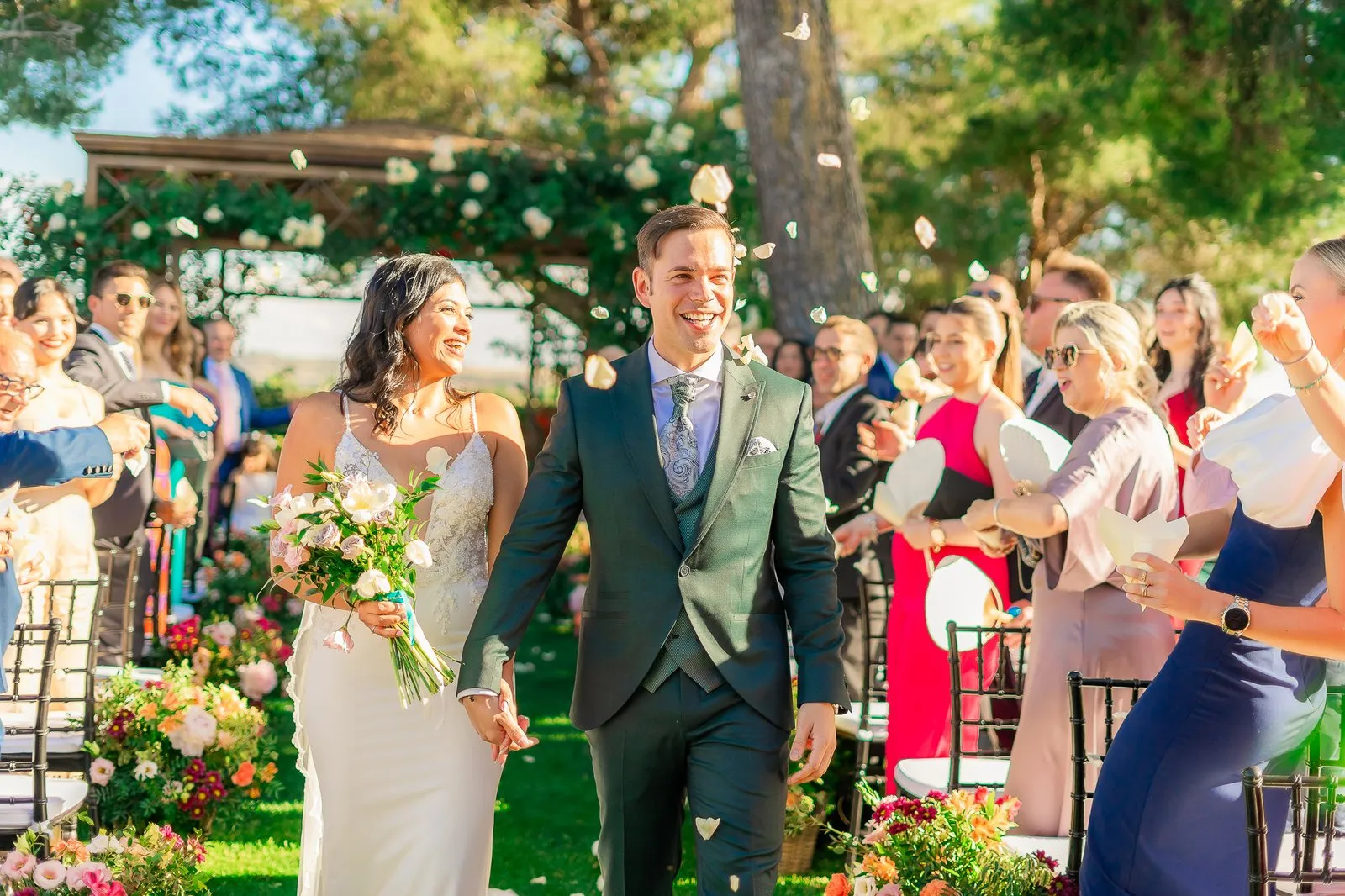 Ceremony in a garden: the couple under a floral arch, guests around them