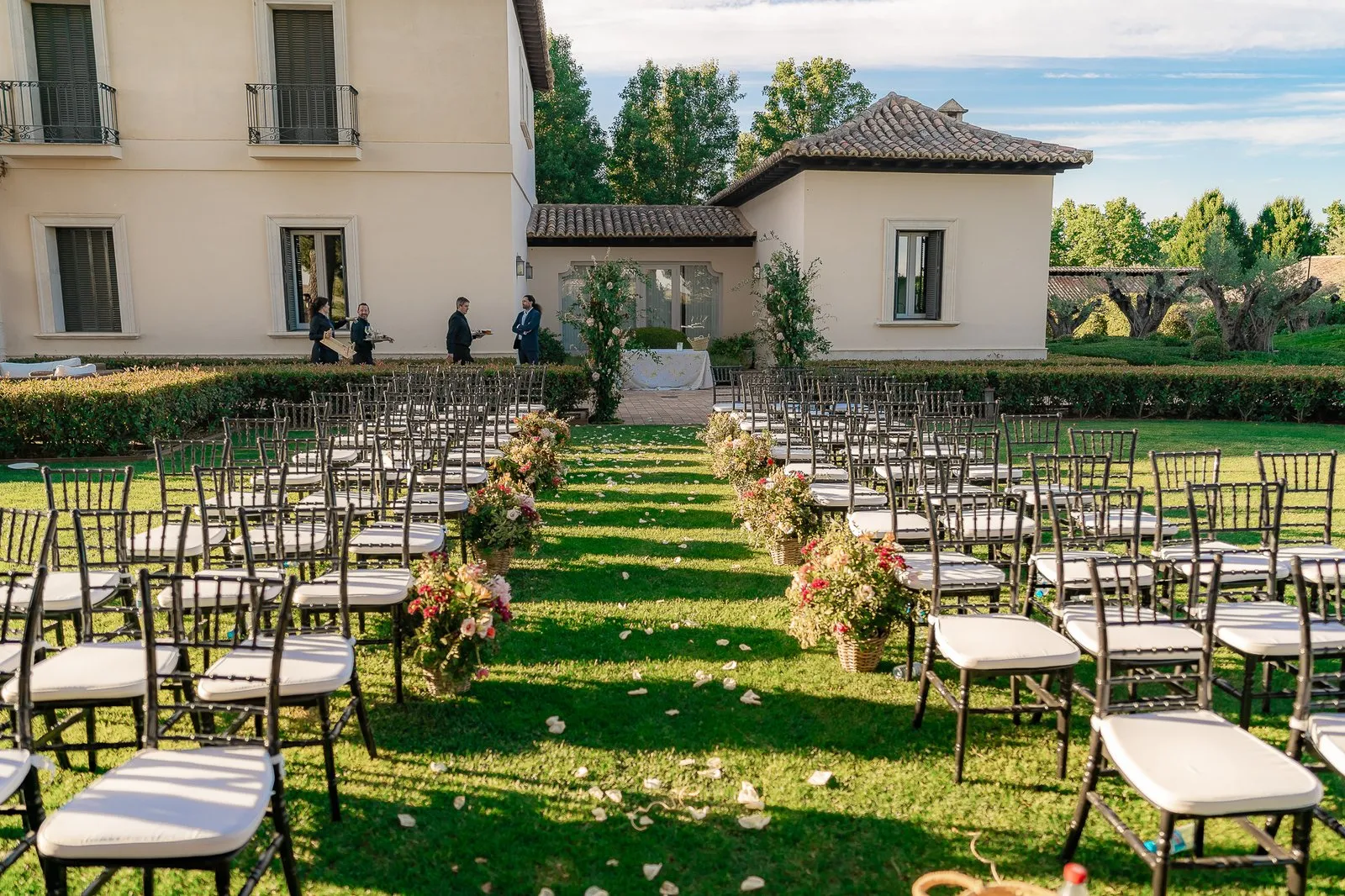 Chairs set out on the lawn in rows before a stately house, ready for a ceremony