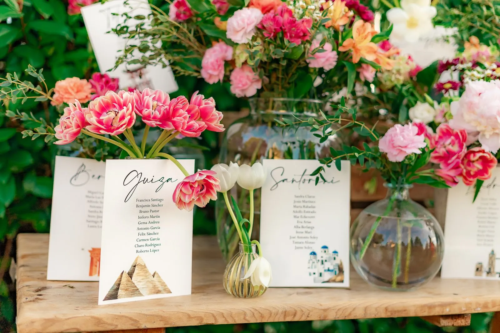 Seating plans named after destinations, among tulips and carnations on a wooden board